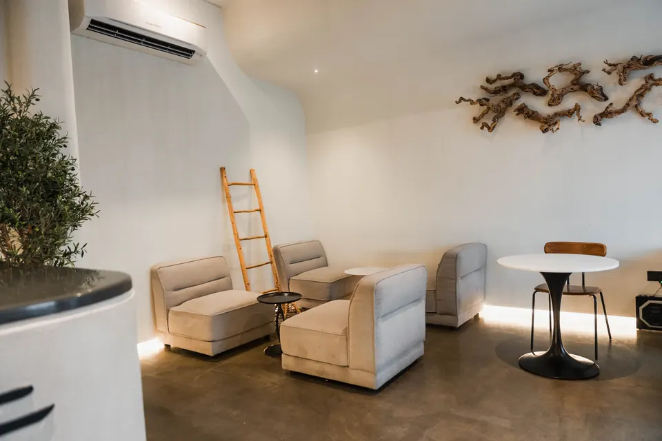 The lounge at Crane: soft cream sofas, round marble tables and a driftwood sculpture on the wall